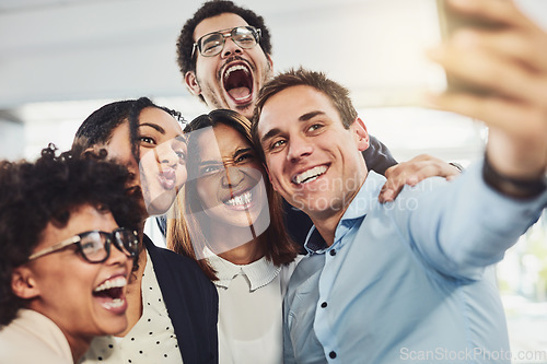 Image of Teamwork, playful and selfie while a group of cheerful businesspeople making funny faces together for a social media post. Faces of a happy and fun team standing together in a creative office