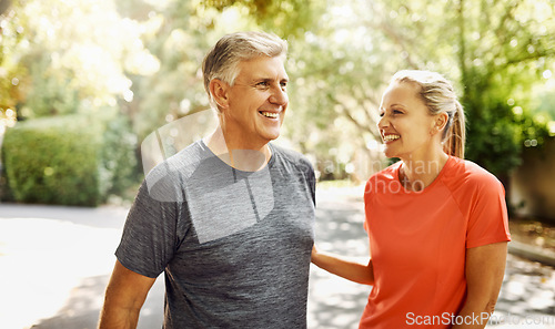 Image of Happy mature couple keeping active, fit and healthy while jogging, running or going for walk outdoors in nature environment. Laughing senior man and woman enjoying a break from workout or exercising