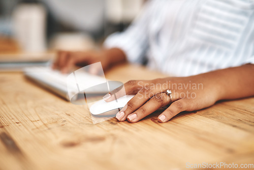 Image of Hand on a mouse, clicking and scrolling while browsing online and surfing the internet. Closeup of a woman using a computer while sitting at a wooden desk. Connection with wireless technology.