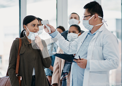 Image of Travel medical healthcare worker testing covid temperature at airport using infrared thermometer. Professional doctor doing a coronavirus check up on a woman at an office entrance