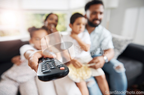 Image of Closeup of remote control with family watching tv in their living room together. Parents and kids relaxing on the sofa enjoying a movie, series or cartoons in the lounge at home while bonding