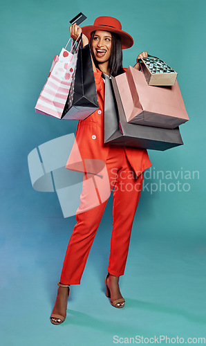 Image of Shopping with credit card, holding bags and enjoying retail therapy spree while standing against a blue studio background. Stylish, elegant and beautiful woman buying items and fashion clothes