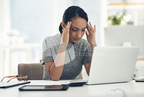 Image of Headache, tired and stressed young businesswoman with financial problems on laptop sitting at desk. Professional female accountant in accounting finance and corporate business doing taxes and debt.