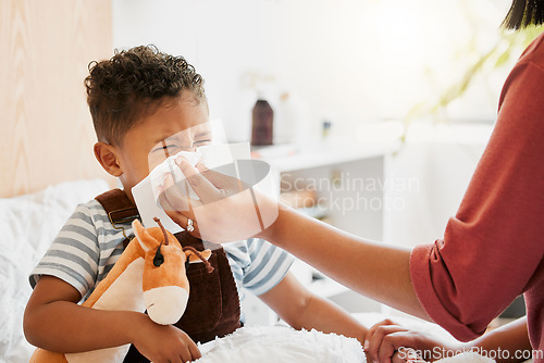 Image of Flu, sick or cold child with parent sneezing, blowing and wiping runny nose while ill with covid virus, sinus and allergy symptoms in bed at home. Mother caring for stuffy and congested little son