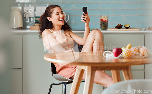 Image of Woman browsing on phone reading social media post with an online app while relaxing in the kitchen. Female relaxing, smiling and enjoying a funny post, video or meme on the internet in the morning