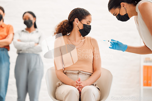 Image of A covid vaccine of a young woman getting vaccinated for work in the office. Young wearing a mask female getting an injection or treatment to prevent the spread of coronavirus at the workplace