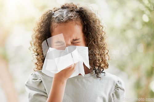 Image of Sick little girl with a flu, blowing her nose and looking uncomfortable. Child suffering with sinus, allergies or covid symptoms and feeling unwell. Kid with a cold sneezing and holding a tissue