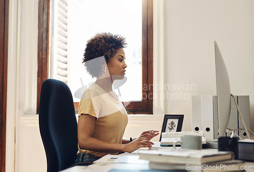 Image of Serious business woman working on computer, reading emails and browsing internet while sitting at a desk in an office at work. Secretary or receptionist checking schedule and planning daily routine