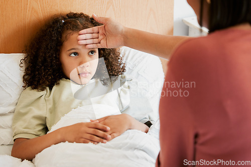 Image of Concerned, anxious and unwell girl suffering with cold or flu while her mother checks her temperature at home. Worried parent caring for her sick child, feeling for fever while worrying about corona