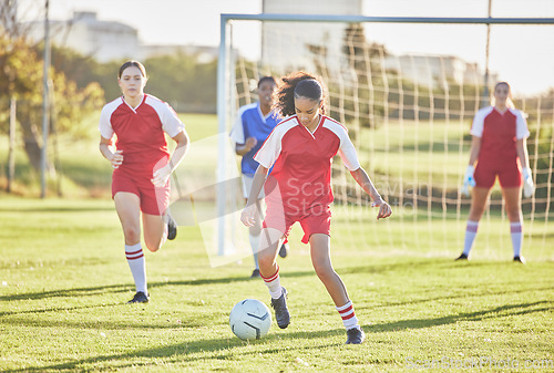 Image of Female football, sports and girls team playing match on field while kicking, tackling and running with a ball. Energy, fast and skilled soccer players in a competitive game against opponents outdoors