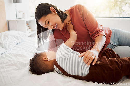 Image of Happy, loving family with a mother and son being playful and bonding on a bed at home. Smiling parent playing with her child, laughing and enjoying motherhood. Single parent embracing her son