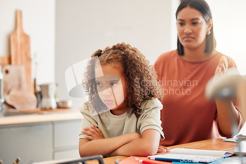 Image of Unhappy, moody and angry little girl standing with arms crossed and looking upset while ignoring her mom. Upset, naughty and problem daughter or child and her angry or disappointed mother at home