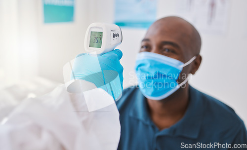 Image of Checking for covid, corona or fever with a patient wearing a mask for hygiene, sickness or flu symptoms in a health clinic. Medical doctor holding a thermometer to scan the temperature of a patient