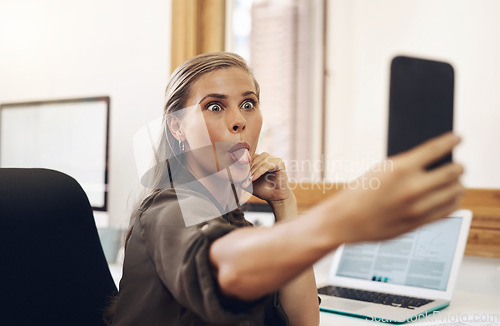 Image of Phone selfie with a playful business woman having fun, being goofy and joking while working in her office. Young female sticking out her tongue and making a face at work while feeling carefree