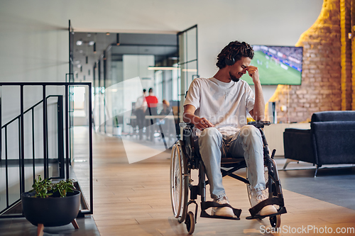 Image of A sad businessman in a wheelchair occupies a hallway within a modern startup coworking center, embodying inclusivity and determination in the business environment