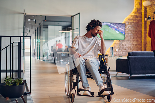 Image of A sad businessman in a wheelchair occupies a hallway within a modern startup coworking center, embodying inclusivity and determination in the business environment