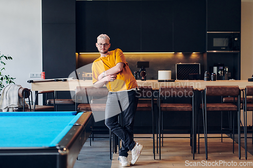 Image of A man takes a brief rest from work in a modern startup coworking center, using the moment to recharge and relax with technology by his side.