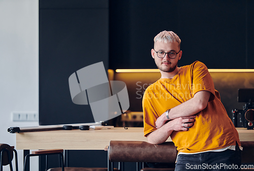 Image of A man takes a brief rest from work in a modern startup coworking center, using the moment to recharge and relax with technology by his side.