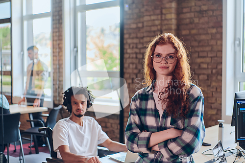 Image of A portrait of a young businesswoman with modern orange hair captures her poised presence in a hallway of a contemporary startup coworking center, embodying individuality and professional confidence.