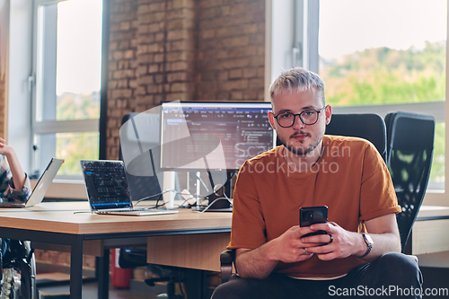 Image of A modern businessman takes a relaxing break from work, using his smartphone to unwind and recharge during his pause