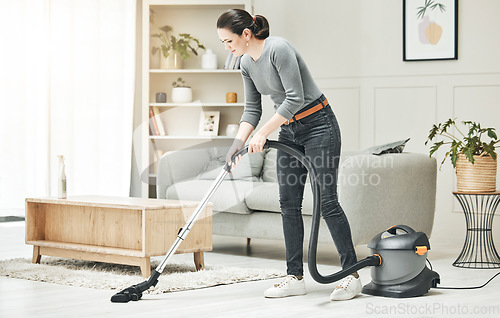 Image of Vacuuming, cleaning and housework done by a mother, house wife or girlfriend using a vacuum cleaner. Stay at home mom, maid or housekeeper doing household chores and tidying in a modern living room