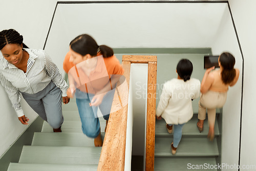 Image of Overhead of busy, diverse female colleagues returning to work after break, with blurred digital tablet screen. Active business woman in motion talking and walking up office building stairs.