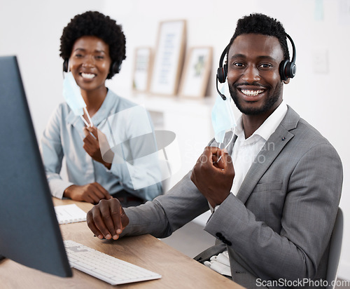 Image of Customer service agents working on computer, helping people online and giving support while sitting together at work. Portrait of smiling African call center agents removing face at end of pandemic