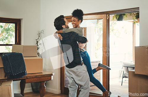 Image of Homeowner couple celebrating, hugging and cheering in new home as real estate investors, buyers and owners. Fun interracial man and woman looking excited, happy and cheerful while embracing by boxes