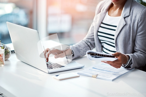 Image of Business woman typing on laptop, reading from notebook and planning a strategy in an office at work. Corporate employee, manager or boss sending emails, completing a proposal and browsing internet