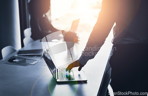 Image of Silhouette of a business man hand working on a laptop at an IT company and having a meeting in an office. A male employee typing in a dark boardroom during a meeting or presentation