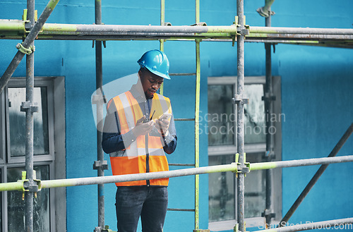 Image of Male construction worker working checking a digital building plan on a phone. Busy urban development builder looking at buildings planning data to give industry information on a two way radio