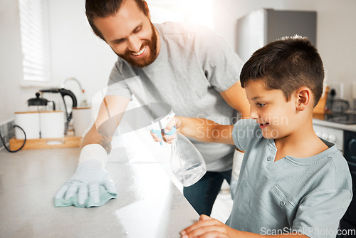 Image of Father teaching young son cleaning chores in the family home having fun and bonding together. Smiling and loving father helping, washing and wiping kitchen counter with his little boy indoors