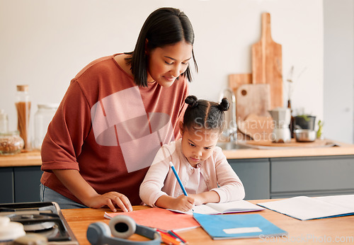 Image of Mother teaching daughter, doing homework at kitchen table at home, bonding while learning together. Loving parent helping her child with a school project or task. Autistic child enjoying homeschool