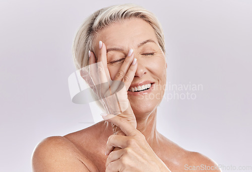 Image of Skincare, wellness and beauty with a senior woman touching her smooth skin and beautiful face with her hand in studio on a grey background. Natural, health and skin care with a female feeling happy