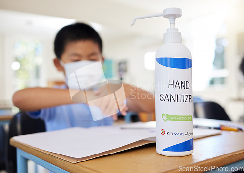 Image of Boy rubbing hand sanitizer for hygiene, safety and protection against covid at school. Closeup bottle of alcohol gel on desk in classroom to clean, kill or prevent the spread of germs or coronavirus