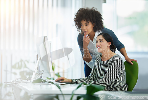 Image of Young creative designers working together on a computer at a desk in a modern office. Women in design thinking, strategy and collaborating at work on a project with technology in the workplace.