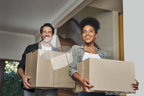 Image of New house, moving and happy couple carrying boxes while feeling proud and excited about buying a house with a mortgage loan. Interracial husband and wife first time buyers unpacking in dream home