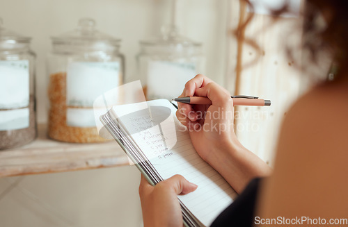 Image of Budget planning, making shopping list and managing household expenses to save money. Financial accountability at home. Woman making shopping list for groceries on a notebook to plan a meal for dinner