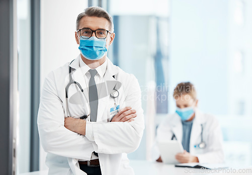 Image of Doctor, physician or healthcare professional with covid face mask in a hospital for medical health insurance background. Innovation, leadership and excellence male gp portrait with his arms crossed