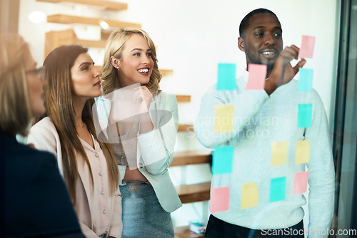 Image of Business people planning, organizing ideas and strategy with sticky notes while thinking, working together on a marketing project. Busy, innovative and creative young professionals work on a solution