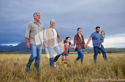 Image of Big happy family walking on field, meadow and countryside in nature to relax, bond and holding hands in love, trust and support. Generation of grandparents, parents and kids having fun outside