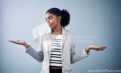 Image of Decisions, choices and options with a young business woman comparing and weighing up different decisions with copyspace in studio against a grey background. Picking between two balanced ideas