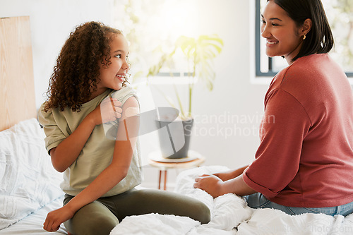 Image of Girl with covid vaccine shows mother vaccinated arm with plaster as covid19 protection for a kid in a bedroom home. Child after getting an injection bonding with her mom in the bedroom