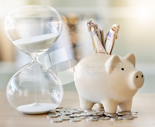 Image of Money, finance and saving with a piggy bank and hourglass on a tablet or desk with time, cash and coins. Financial investment, retirement or planning for the future with a .budget and growth strategy