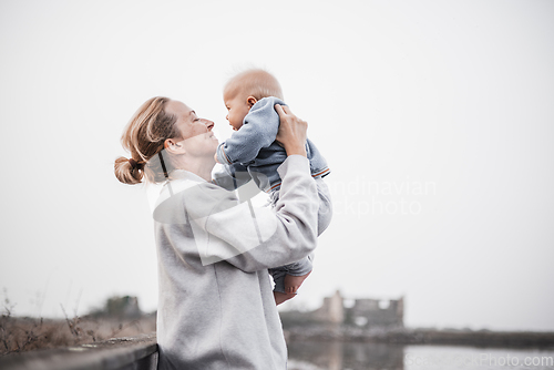 Image of Tender woman caressing her little baby boy infant child outdoors on autumn trip to Secovlje salinas landscape park, Slovenia. Mother's unconditional love for her child.