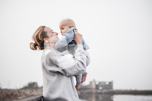 Image of Tender woman caressing her little baby boy infant child outdoors on autumn trip to Secovlje salinas landscape park, Slovenia. Mother's unconditional love for her child.