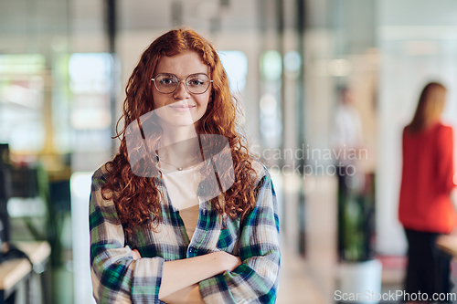 Image of A portrait of a young businesswoman with modern orange hair captures her poised presence in a hallway of a contemporary startup coworking center, embodying individuality and professional confidence.