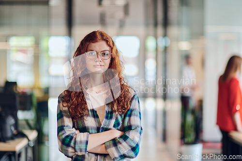 Image of A portrait of a young businesswoman with modern orange hair captures her poised presence in a hallway of a contemporary startup coworking center, embodying individuality and professional confidence.