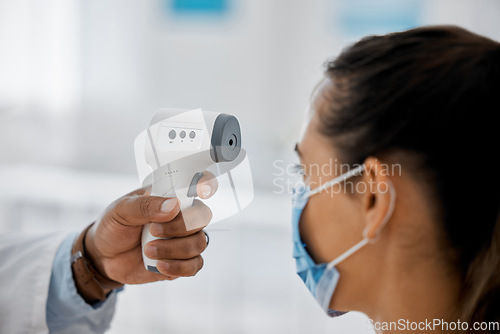 Image of Compliance, healthcare and covid with a doctor scanning a patient temperature with infrared thermometer, checking for a fever. Concerned woman suffering from corona, flu or cold in exam or consult