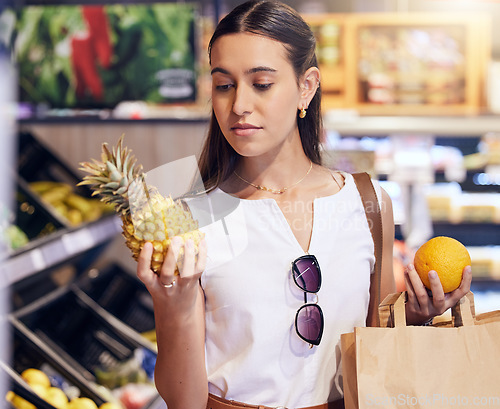 Image of Shopping, holding and looking at fruit at shop, buying healthy food and examining items at a grocery store. Woman deciding, choosing and picking ripe, fresh and delicious produce alone at a market